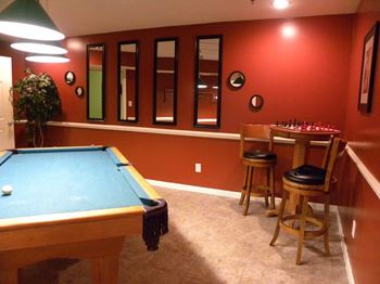 A pool table with a green cloth and a white ball is in the center of the room.